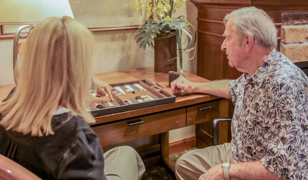 Women helping an elderly man with a puzzle to work on his memory care